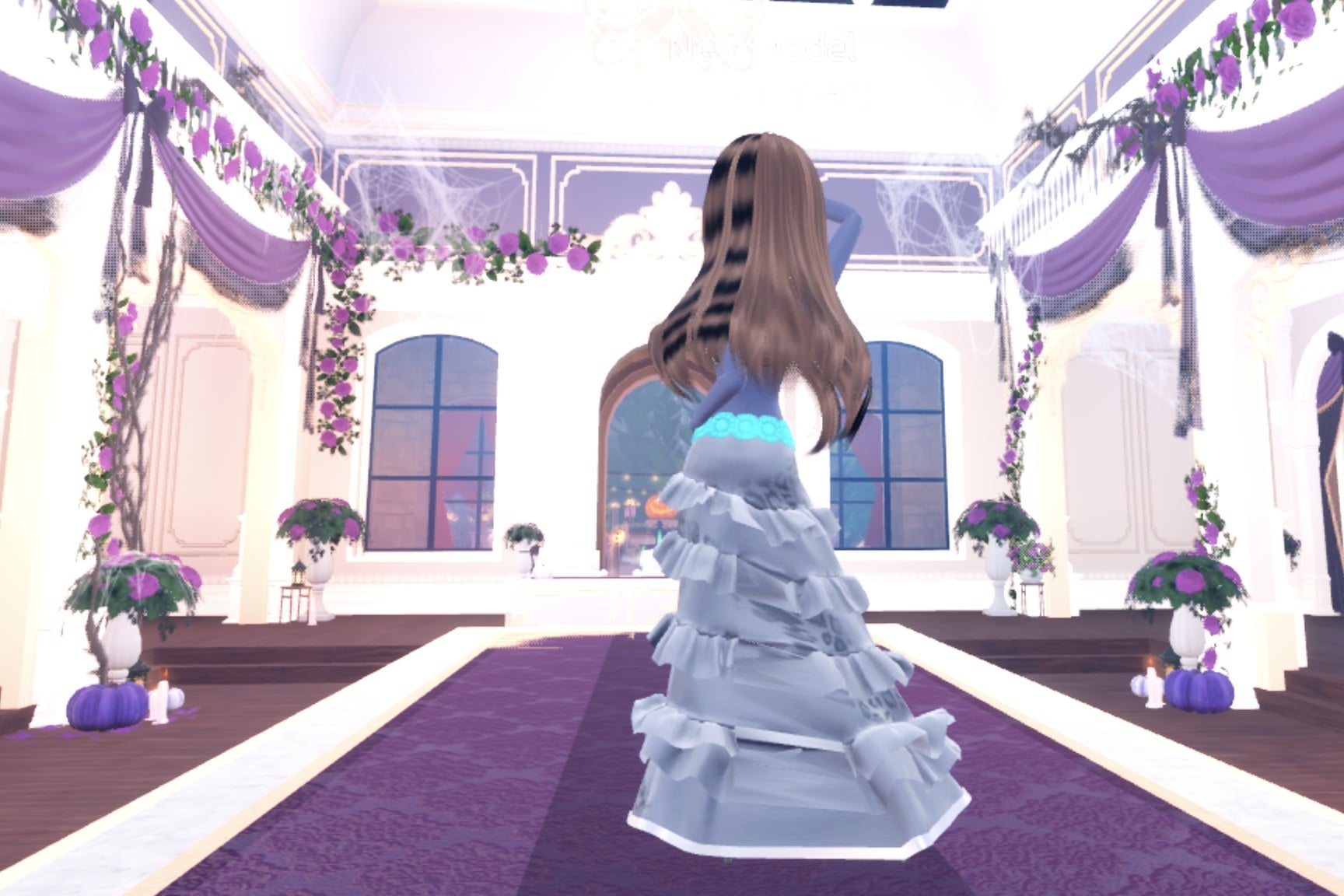 Back view of the metallic silver gown: long wavy hair over the shiny silver tiers and a cyan belt
