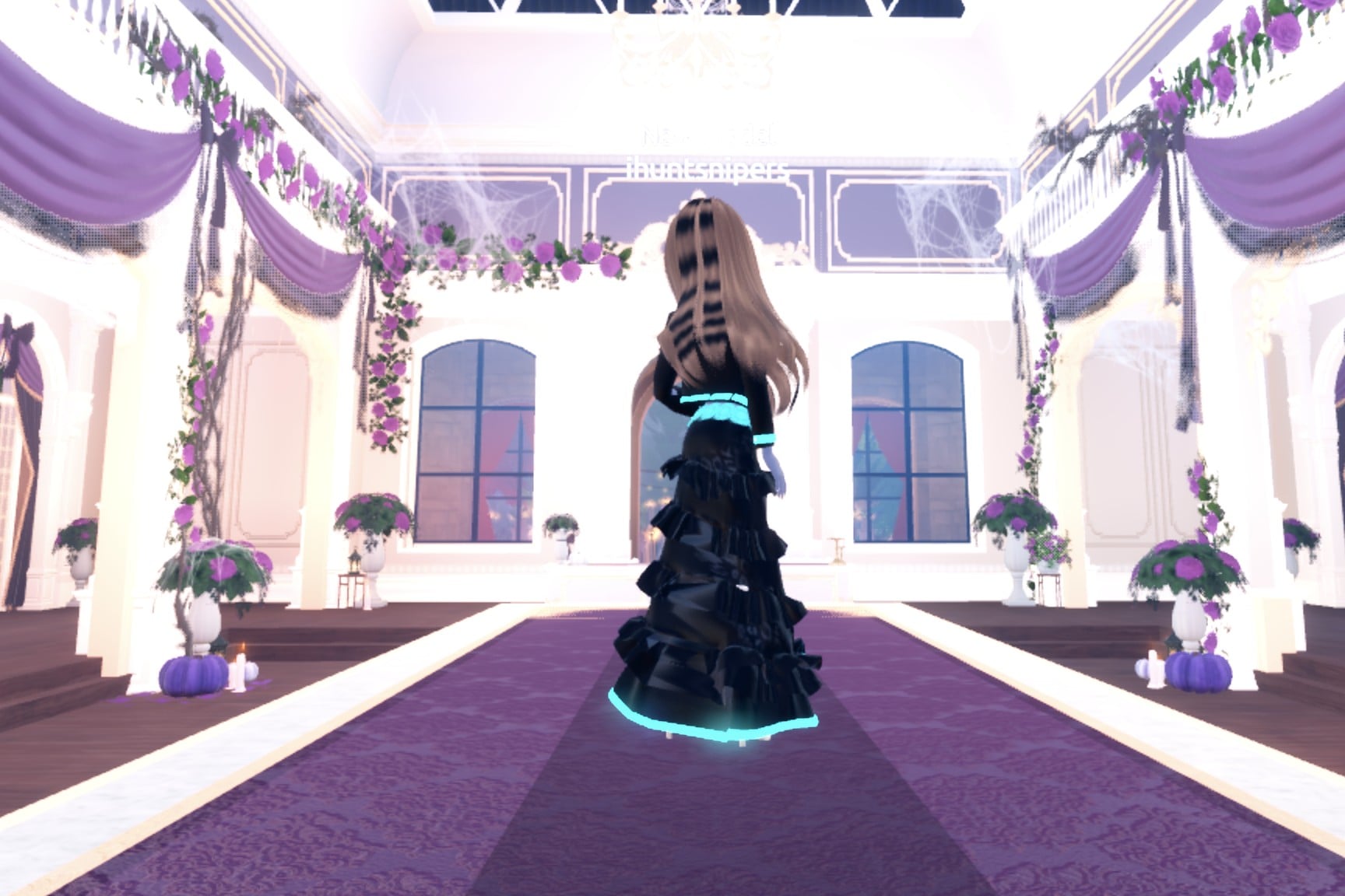 Back view of the black chrome cyborg look: black jacket and gown with a glowing cyan hem and belt