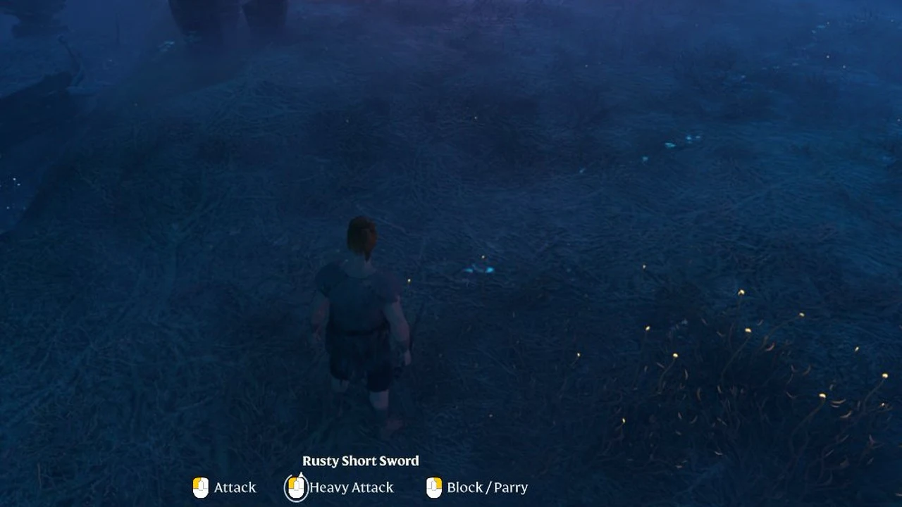 Character crossing a dark cavern floor with Rusty Short Sword attack, heavy attack and block controls shown