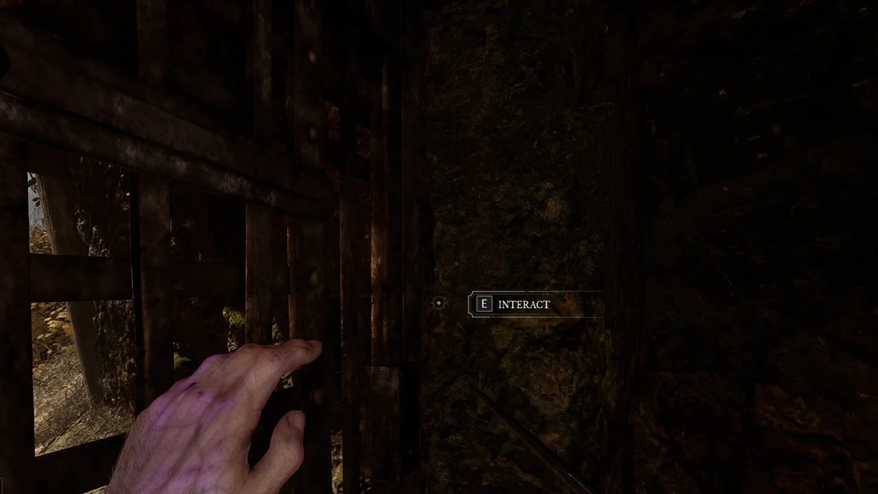 E INTERACT prompt showing beside the barred wooden gate in the cave tunnel