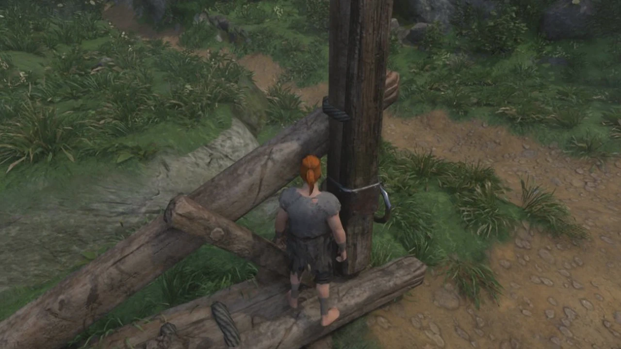 Character beside a wooden fence post and log barrier on a dirt path