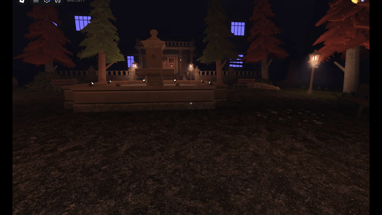 Dark courtyard with a stone fountain in the centre of the path and the manor behind it
