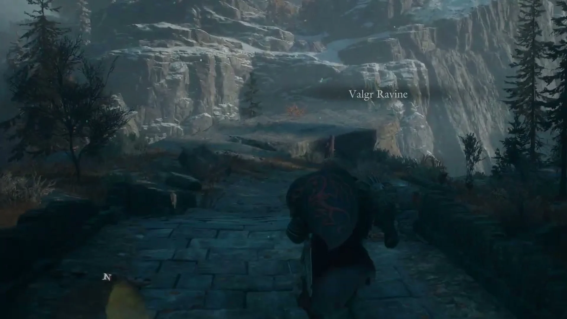 The paved road outside the stone archway with the area name Valgr Ravine on screen
