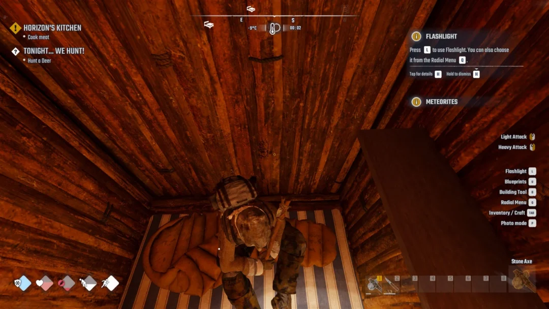 A survivor lying on a sleeping bag inside a wooden bunkhouse seen from above