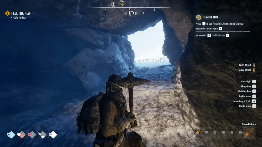 A survivor with a pickaxe inside the first cave, facing its bright snowy exit