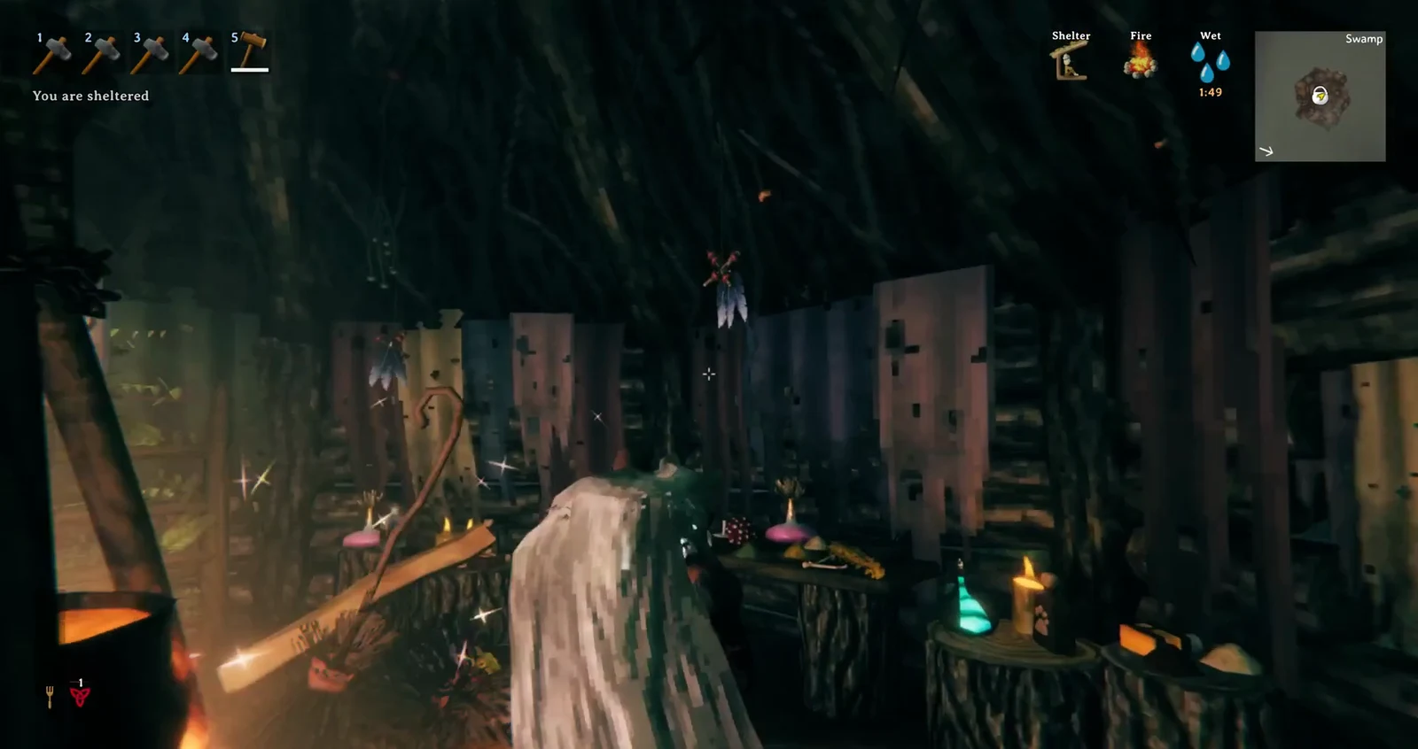 Standing inside the firelit hut interior with candles, bottles and herbs on stump tables