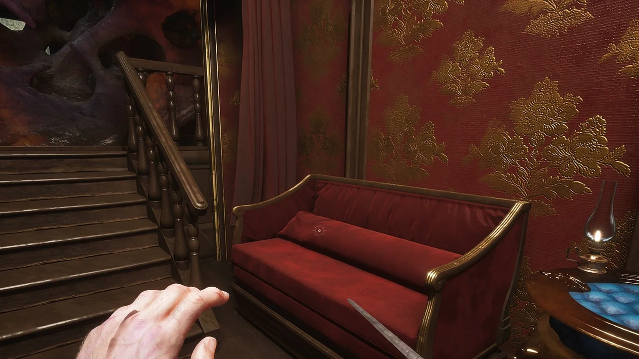 First-person crosshair on a cushioned display case beside a staircase in a red-papered room
