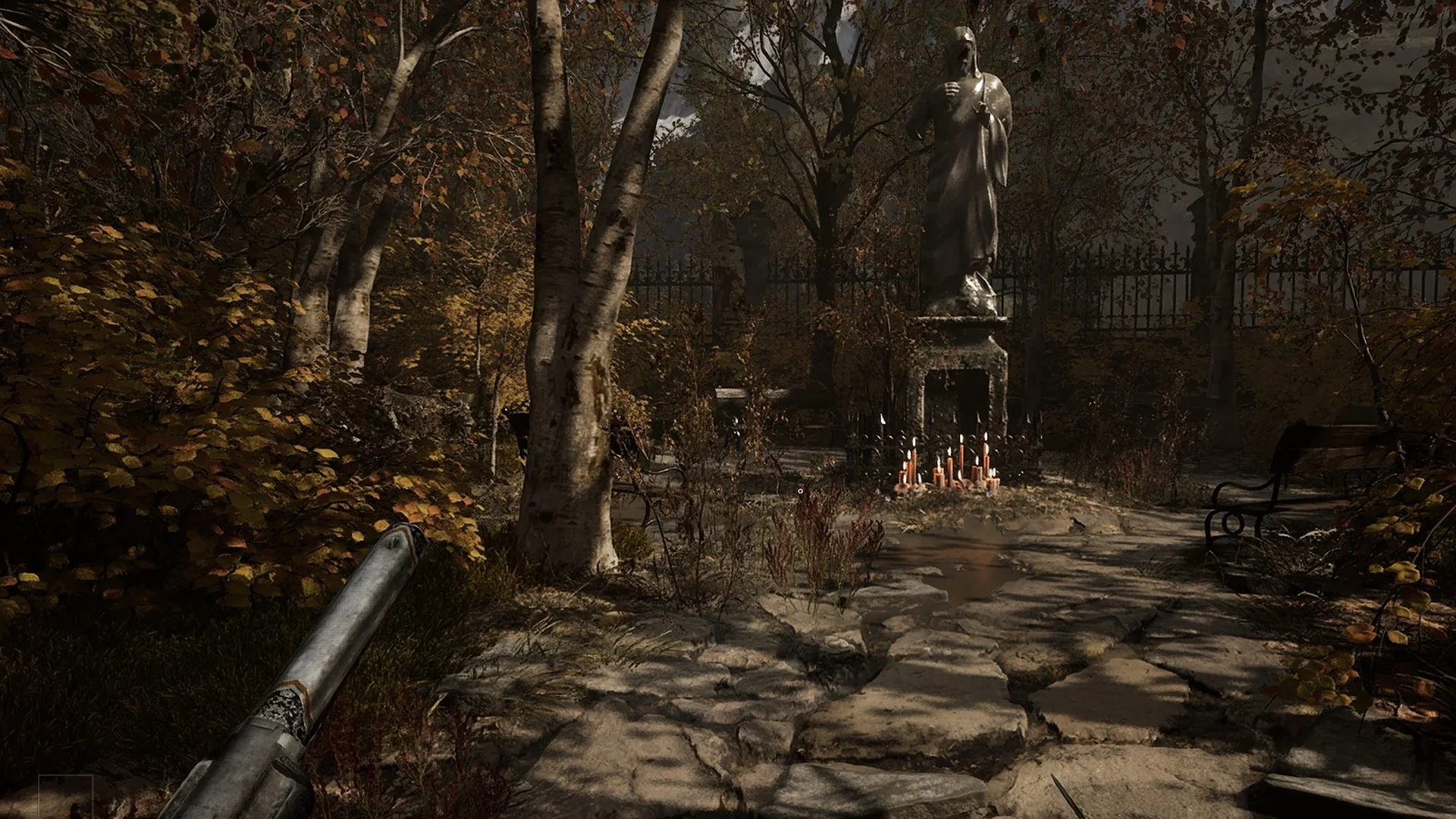 A hooded stone statue with candles at its foot in the churchyard garden behind the Abandoned Church in Valor Mortis